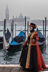 Fototapeta na wymiar Karneval in Venedig, maskierte Dame mit Gondeln und San Giorgo Maggiore im Hintergrund