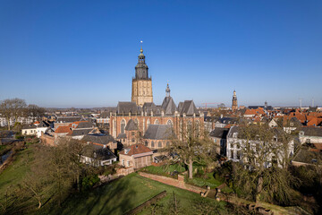 Fototapeta na wymiar Medieval city wall and authentic historic tower town Zutphen gardens with Walburgis church towering over the medieval rooftops against a clear blue sky