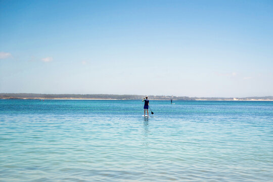 Man Wearing Rash Guard On A Stand-up Paddle Board At The Ocean Bay In Australia. SUP Water Sport Activity