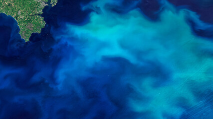 Fototapeta na wymiar Aerial turquoise ocean photo from clear sky, top view of sea texture background, 16:9 ratio wallpaper, blooms of phytoplankton in the waters around England, Elements of this image furnished by NASA.