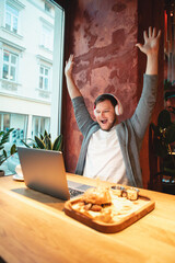 man freelancer working on laptop in cafe eating burger and drinking tea