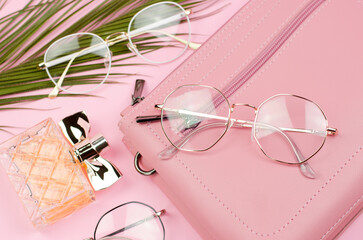 Stylish gold-framed glasses. Stylish glasses and a pink women's bag on a pink background.