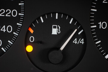 Car fuel gauge scale with orange reserve light on. Close up macro shot, no people