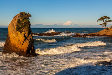 横須賀市秋谷立石公園から荒波洗われる岩礁と朝の富士山