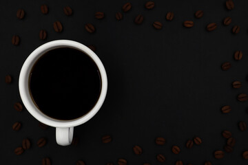 top view of white ceramic cup hot coffee roasted coffee beans on a dark background