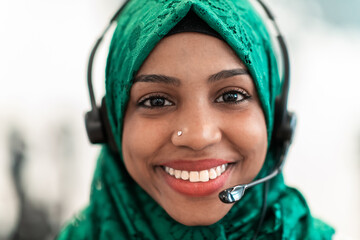 Afro Muslim female with green hijab scarf customer representative business woman with phone headset...