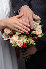 Obraz na płótnie Canvas Hands of bride and groom with rings on wedding bouquet. Marriage concept