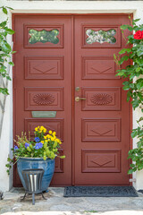 Old red wooden entrance door with flowers and decorations