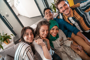 Group of business people during break from the work taking selfie picture while enjoying free time in relaxation area at modern open plan startup office. Selective focus 