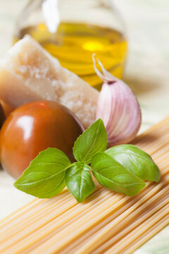 An arrangement of spaghetti, garlic, tomato, Parmesan cheese and basil