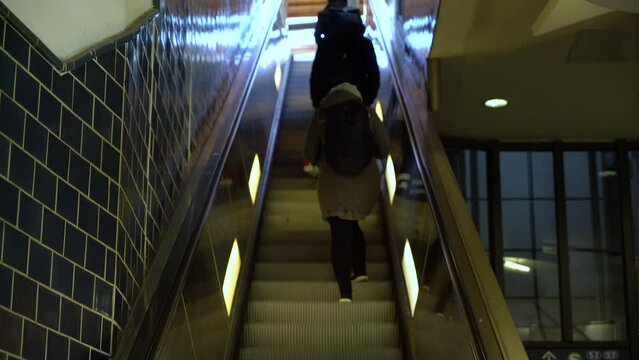 Anonymous people on e scalator in airport, station or shopping mall moving staircase going up
