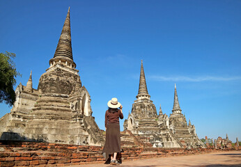 Female Tourist Visiting the Incredible Historic Pagoda Ruins of Wat Phra Si Sanphet in Ayutthaya Historical Park, Thailand - obrazy, fototapety, plakaty