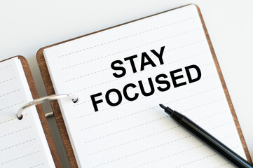 STAY FOCUSED text written in a notebook on a table next to a black marker, business concept