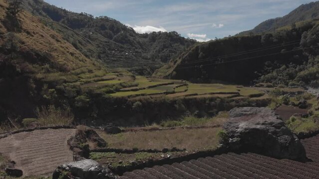 Terrace fields farms vegetable paddy sprinklers spraying water revealing a mountainous valley fast aerial reversing wide angle reveal in kabayan benguet philippines