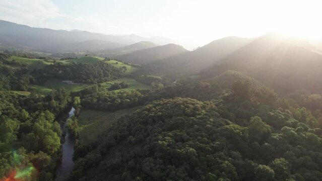 Beautiful sunset just above the mountain peaks of the vast tranquil Valles Pasiegos in the Spanish province of Cantabria in Spain. Drone panning shot