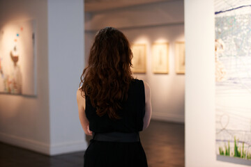 Taking in a century of art. Shot of a young woman looking at paintings in a gallery.