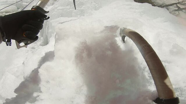 Man climbing ice waterfall with rope and ice axe