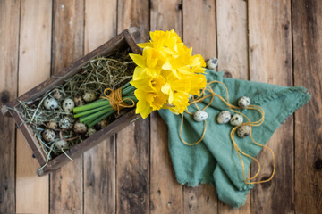 Blumenstrauß mit Narzissen in Ziegelform, Dekoration für den Frühling in Holzkiste mit Blumen, Eiern und Federn rustikal dekoriert, Dekoration für Ostern