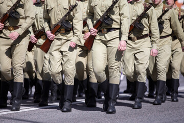 Russian soldiers in tarpaulin boots with weapons are in the ranks.