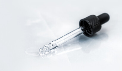 Pipette with fluid hyaluronic acid on blue background. Cosmetics and healthcare concept closeup. Dose of serum, retinol with air bubbles. Flat lay. Luxury beauty product presentation, macro