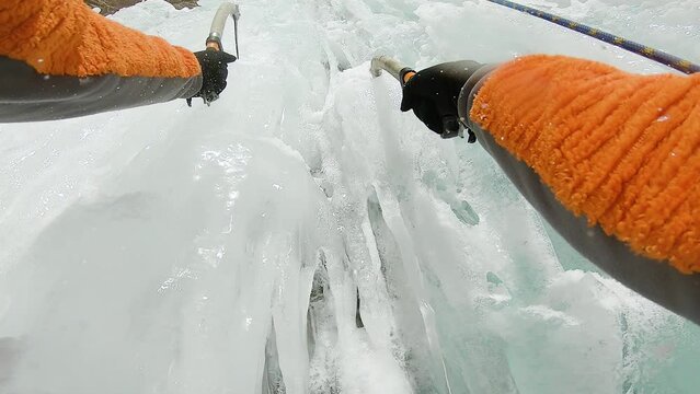 Man climbing ice waterfall with rope and ice axe