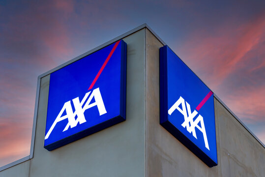 Fossano, Italy - February 22, 2022: Axa logo on illuminated signs on building on colorful after sunset sky,  Axa is French insurance and bank services company