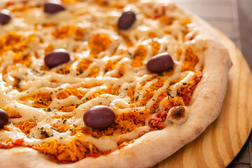 Pizza. Chicken pizza with catupiry cheese and olives on wooden shovel close-up.