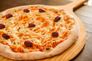 Pizza. Chicken pizza with catupiry cheese and olives on wooden shovel close-up.