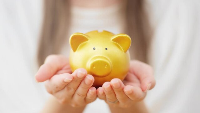 ブタの貯金箱を持つ若い女性