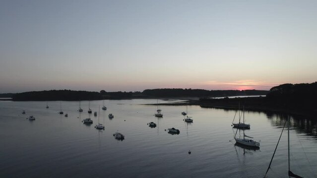 A crone clip of several sail ships anchored in the bay during magical sunset in France Europe.