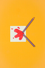 Broken pencil on yellow background, blood drawing
