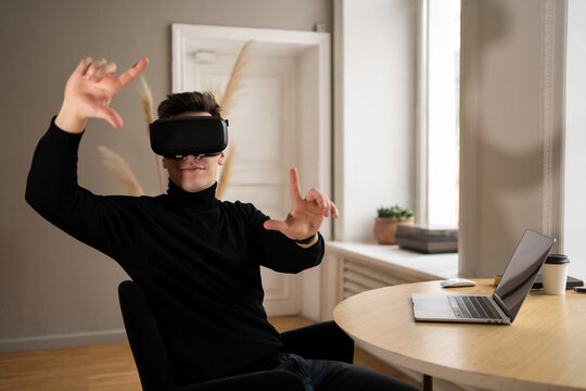 A man with virtual reality glasses uses a laptop computer in the office company report