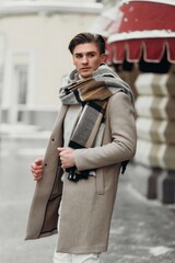  Young man wearing coat walking in the street. Young bearded guy with modern hairstyle in urban background