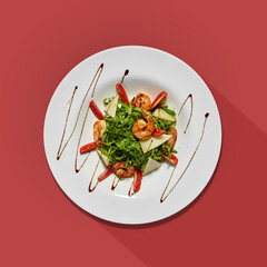 Plate with shrimps, cheese and arugula isolated on color background