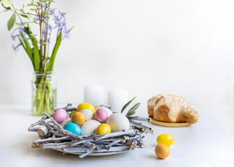 Holiday composition for Easter. Nest with colour and white eggs, candles, hyacinths and colomba