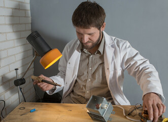 a man soldering iron solders a part from an electrical appliance. the concept of repair of equipment.