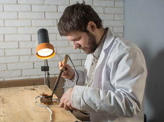 a man soldering iron solders a part from an electrical appliance. the concept of repair of equipment