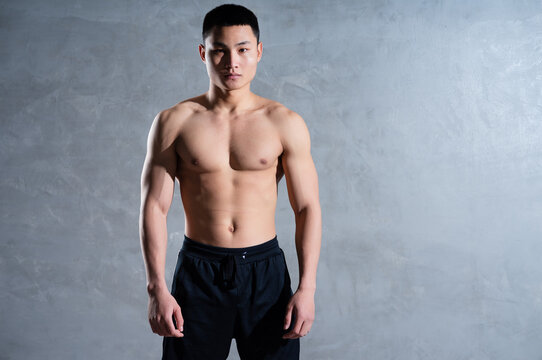 Muscular Asian man posing on gray background