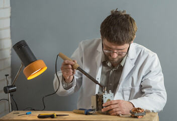 a man in a white coat is sitting in his hands with a soldering iron and a spare part for an...
