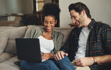 Were updating all our blogs today. Shot of a happy young couple using a laptop while relaxing on a couch in their living room at home. - obrazy, fototapety, plakaty
