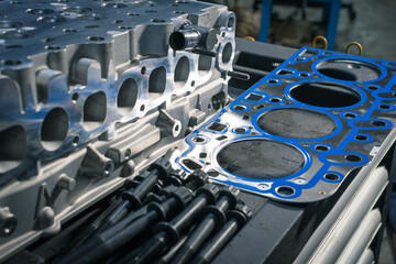 New cylinder head with gasket and bolts on a table in a car repair shop. Blur effect.