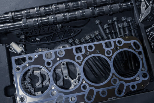 A new cylinder head gasket with various timing parts on a table in a car repair shop. Top view