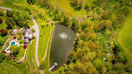 Aerial View of Countryside of Homes With a Pond and Fountain Viewed by a Gazebo on a Sunny Day