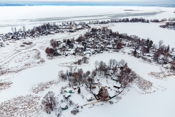 Aerial view of village in middle of frozen creek on winter day after snowfall