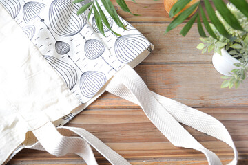 reusable shopping bag on wooden background with plants and candle