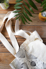 reusable shopping bag on wooden background with plants and candle