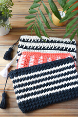 crocheted toiletry bag on wooden background with plants and candle