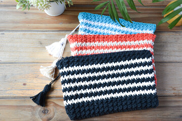 crocheted toiletry bag on wooden background with plants and candle