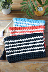 crocheted toiletry bag on wooden background with plants and candle