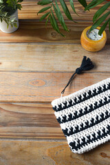 crocheted toiletry bag on wooden background with plants and candle